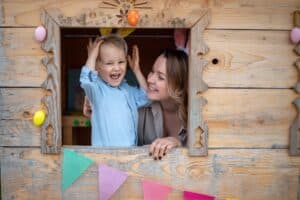 Mutter und Kind schauen aus dem Fenster eines Spielhauses