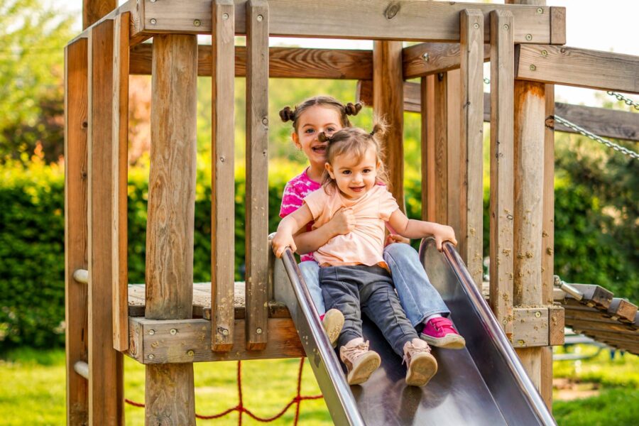 Zwei Kinder rutschen gemeinsam vom Spielturm