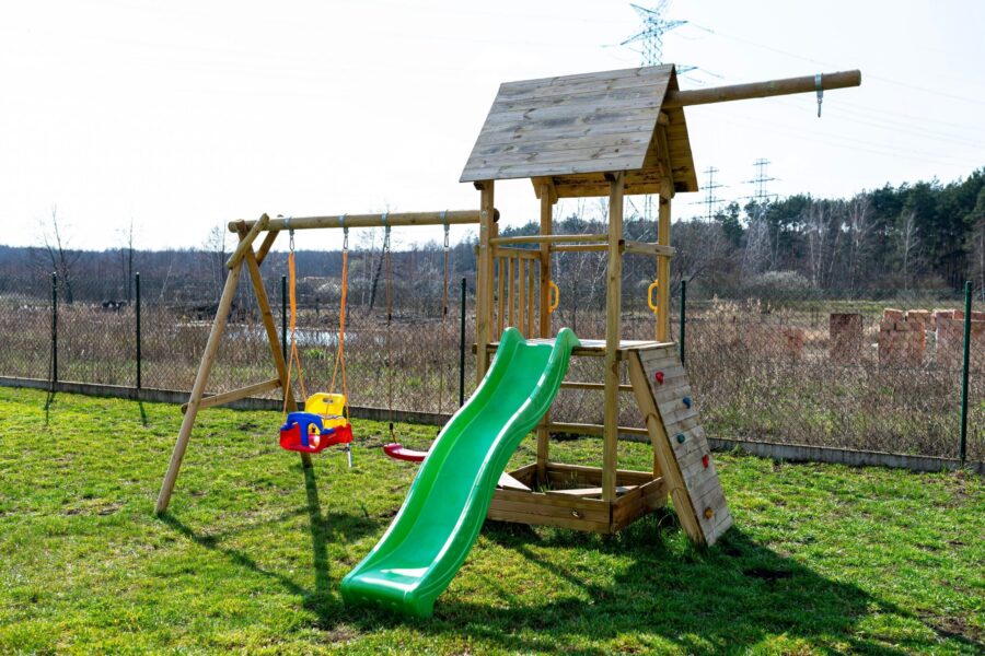 Ein Spielturm mit Rutsche, Schaukel und Kletterwand im Garten