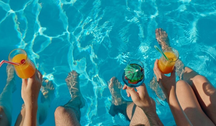 Three,Friends,Sitting,On,The,Edge,Of,A,Pool,With