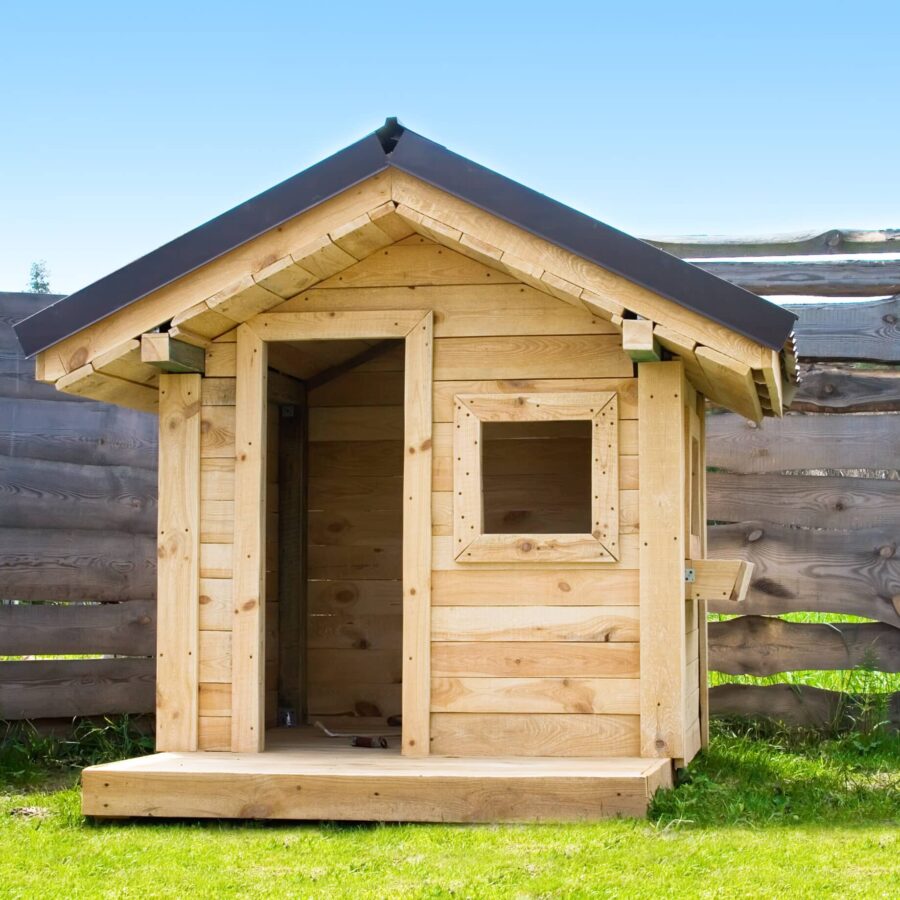 Kinderspielhaus aus Holz vor einem hölzernen Sichtschutz