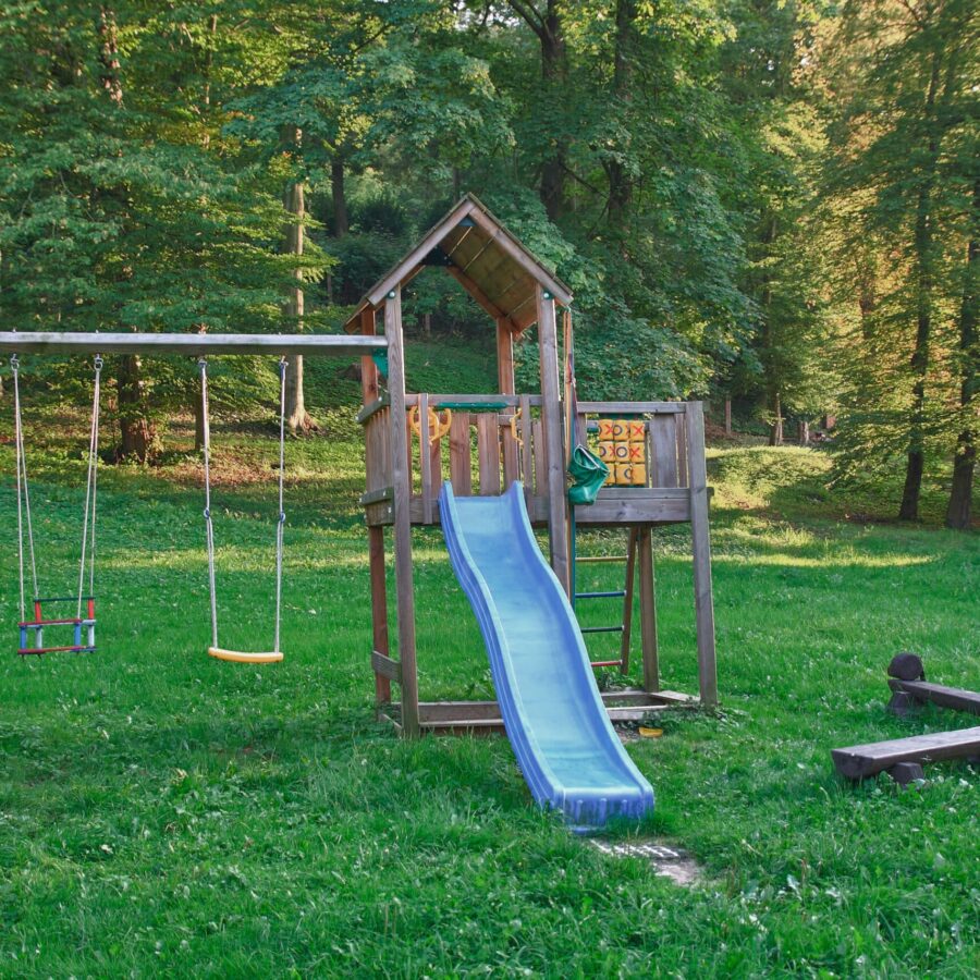 Hölzerner Spielturm in einem weitem, grünem Garten