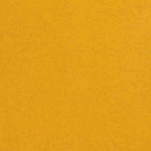 Strukturierte Wandoberfläche in Senfgelb mit feiner Körnung und unregelmäßiger Maserung.