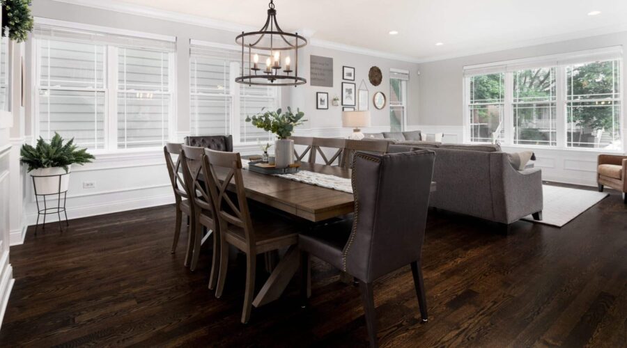 Dunkelbrauner Holzboden in einem hellen Ess- und Wohnzimmer mit Holztisch, Stühlen und Sofas.