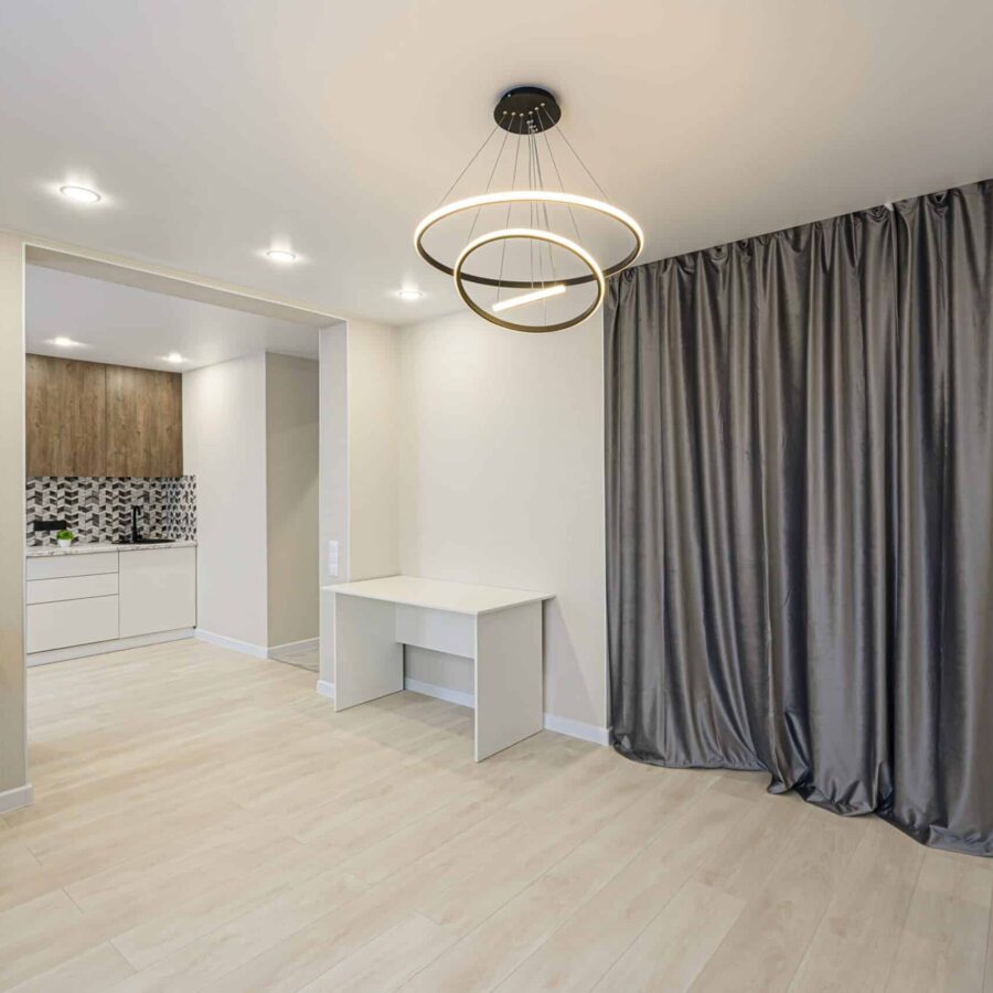 Heller, glatter Holzboden in einem modernen Raum mit grauen Vorhängen, weißem Schreibtisch und Deckenleuchte.