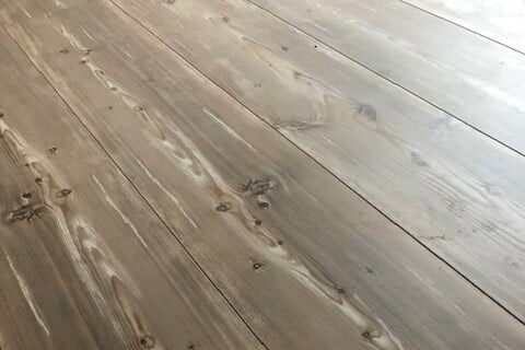 Laminat 2 Nahaufnahme von Laminatboden mit Holzmaserung und sichtbaren Knoten in brauner Farbe.